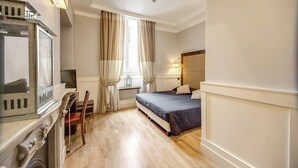 Una habitación de hotel con una cama, un escritorio con televisor y una ventana con cortinas.