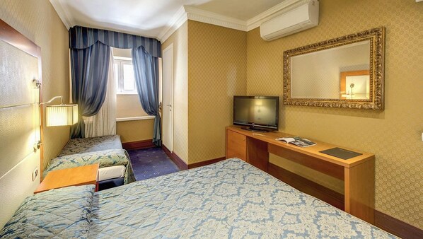 Une chambre d’hôtel avec deux lits, une télévision, un bureau, un miroir et une fenêtre avec des rideaux.
