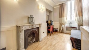 Una habitación con chimenea, un escritorio con silla, una cama y una ventana con cortinas.