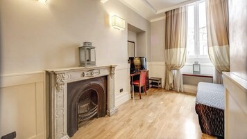 Una habitación con chimenea, un escritorio con silla, una cama y una ventana con cortinas.