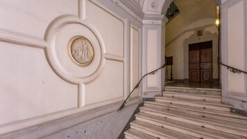 Una gran escalera con molduras ornamentales y un medallón decorativo en la pared.