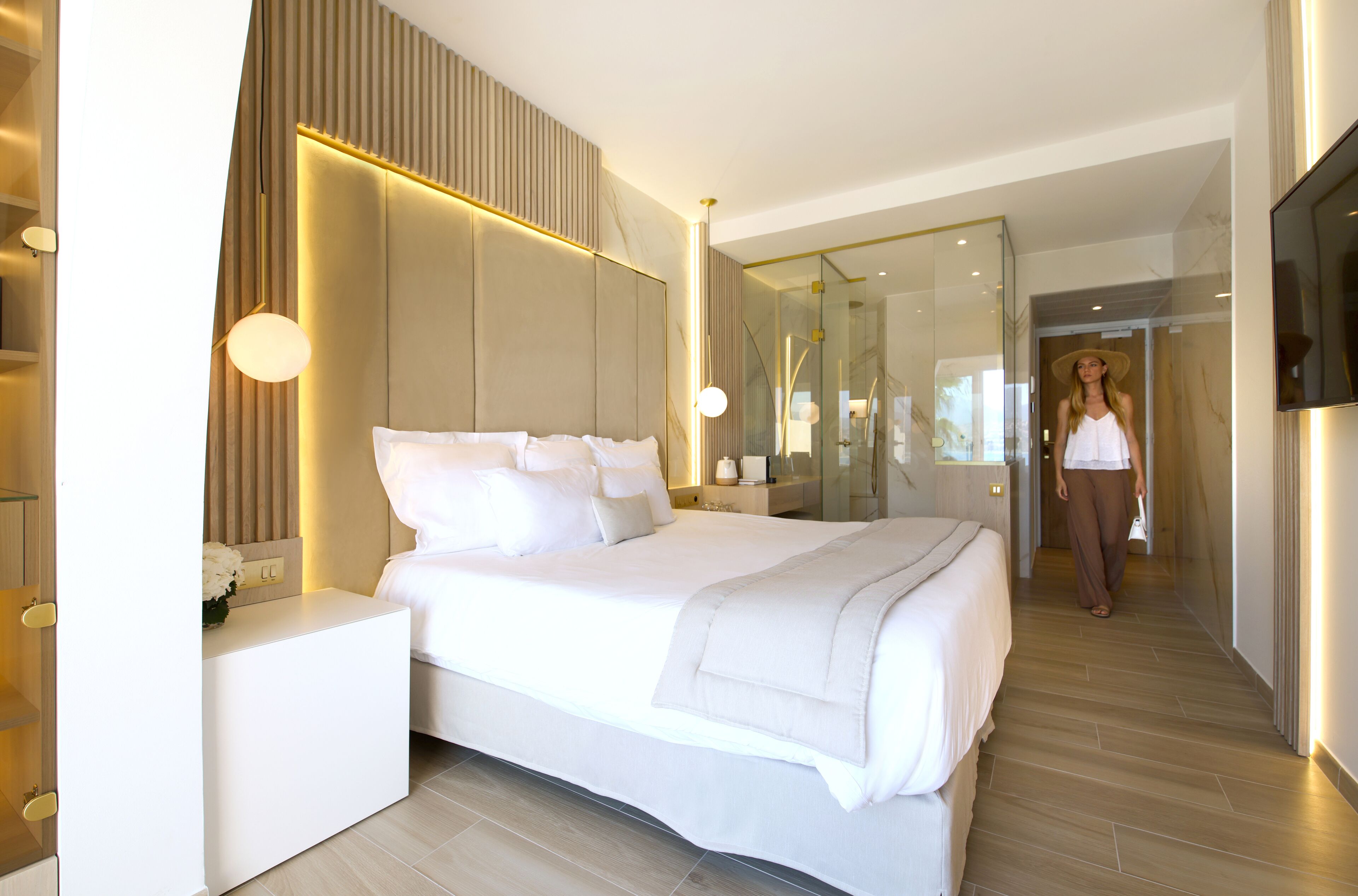 Ein modernes Hotelzimmer mit einem großen Bett, Nachttischen, einem Spiegel und einem Fernseher.