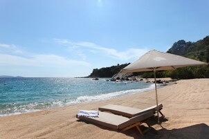 Na praia, espreguiçadeiras, guarda-sóis, toalhas de praia 