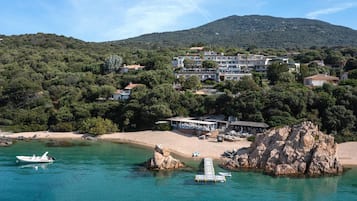 A coastal hotel with multiple buildings, a beach, and rocky outcrops.