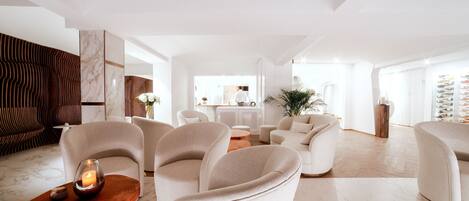 A spacious living area with modern furniture, a central coffee table, and a view of the kitchen in the background.