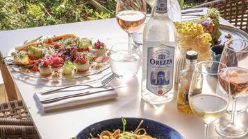 A table set with a variety of dishes, including a seafood platter and pasta, accompanied by wine glasses and a bottle of OREZZA.