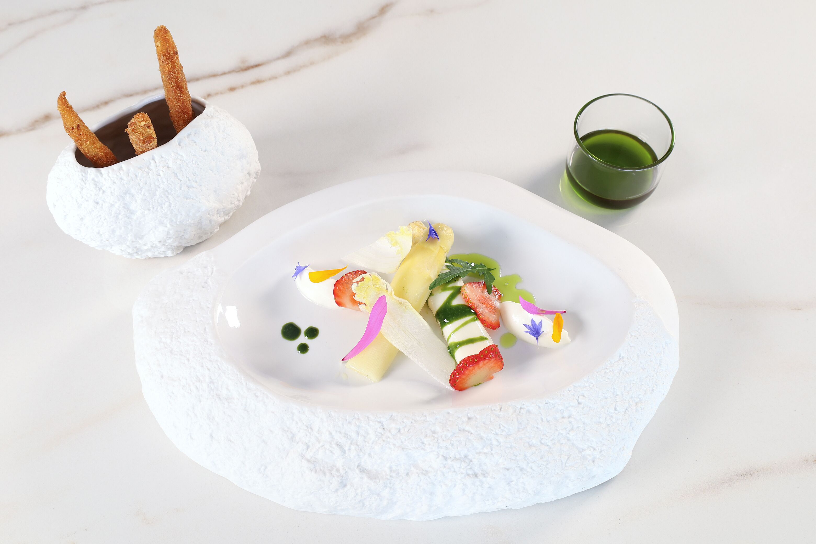 Une assiette de dessert avec divers fruits et un petit verre contenant un liquide vert.