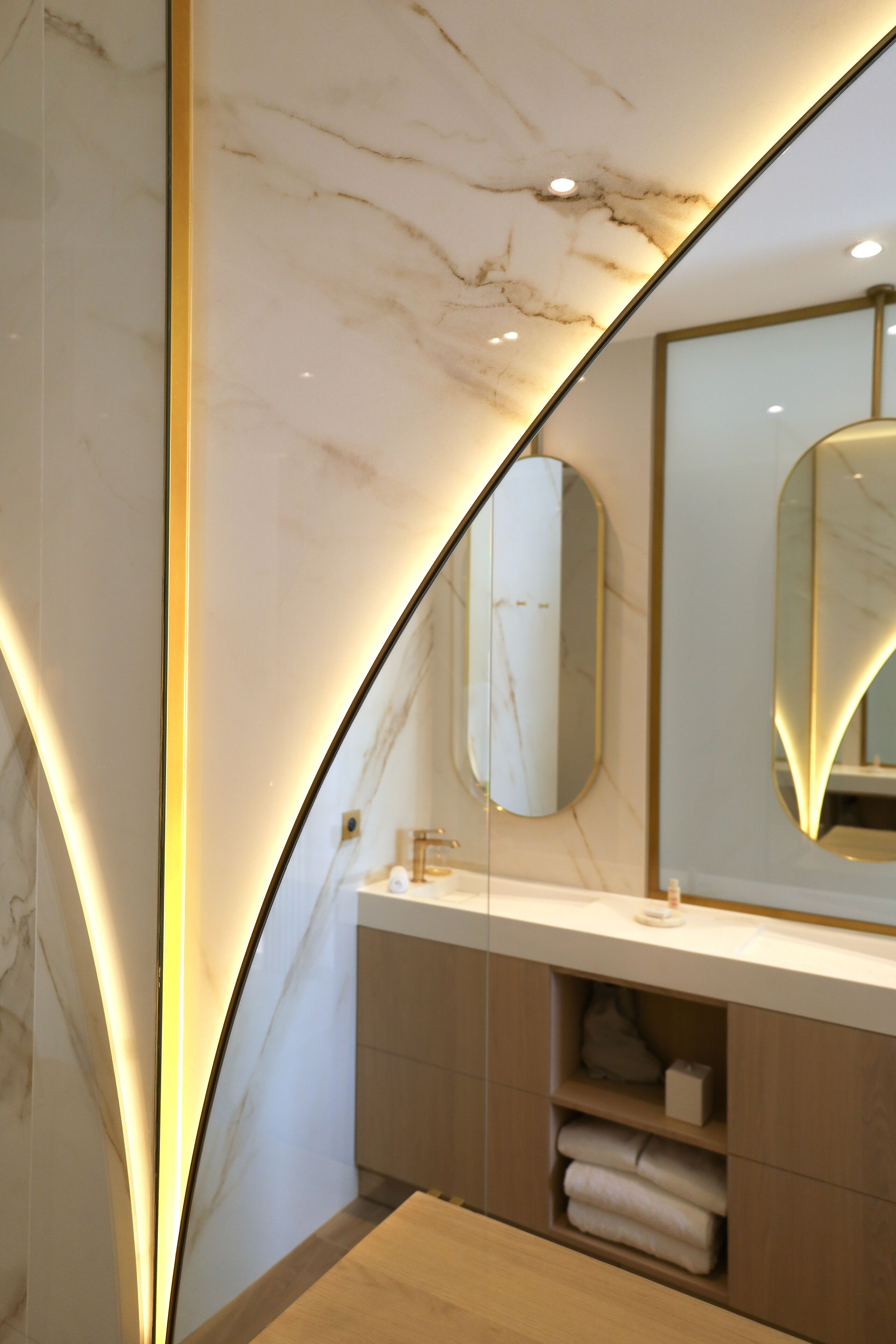 A modern bathroom with a marble ceiling, a large mirror, and a wooden vanity.