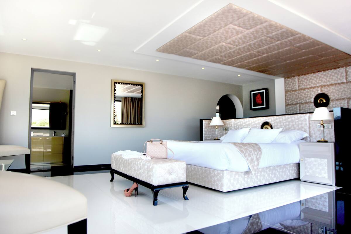 A modern bedroom with a large bed, bedside tables, a vanity, and a mirror.