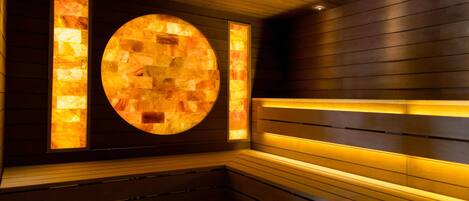 A sauna with wooden walls and a circular heated stone feature.