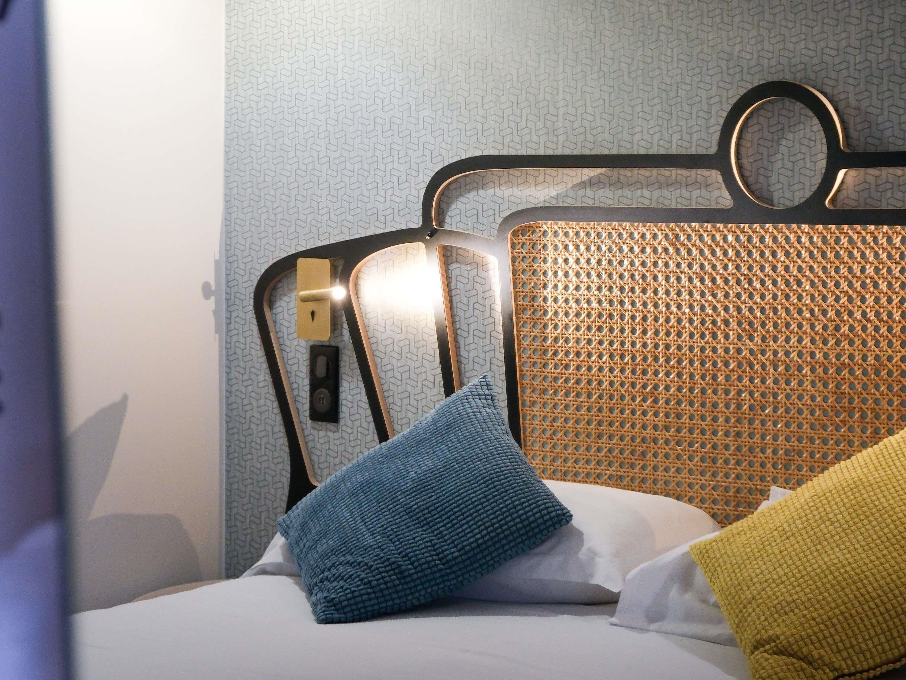 A bed with a metal headboard, two pillows, and a wall with a geometric pattern.