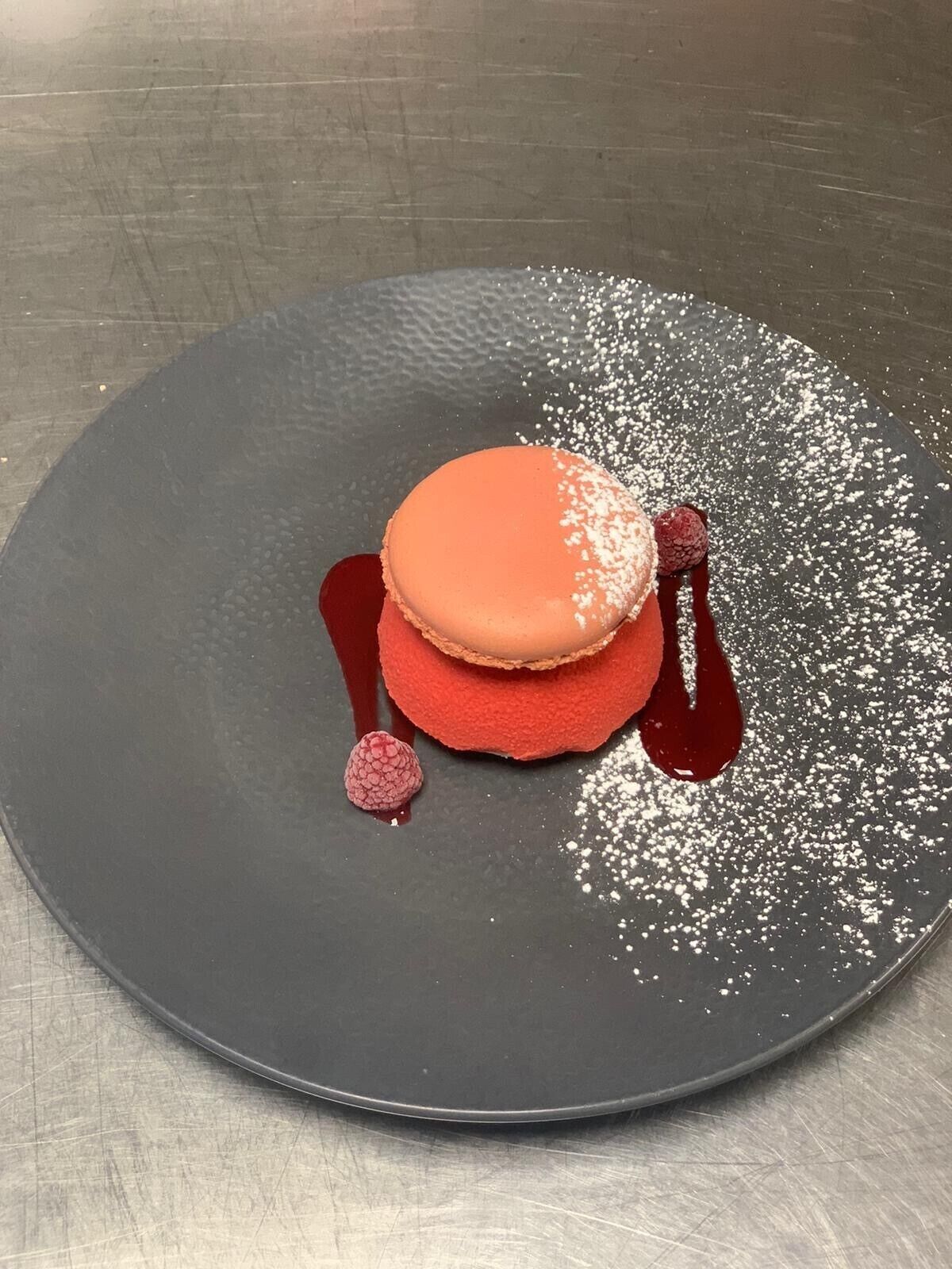Un postre sobre un plato oscuro con superficie texturizada.