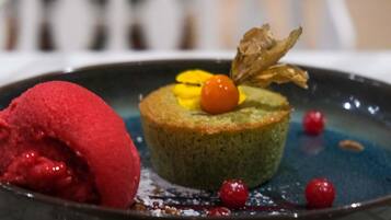 A dessert with a green base, a red scoop, and a cherry on top.