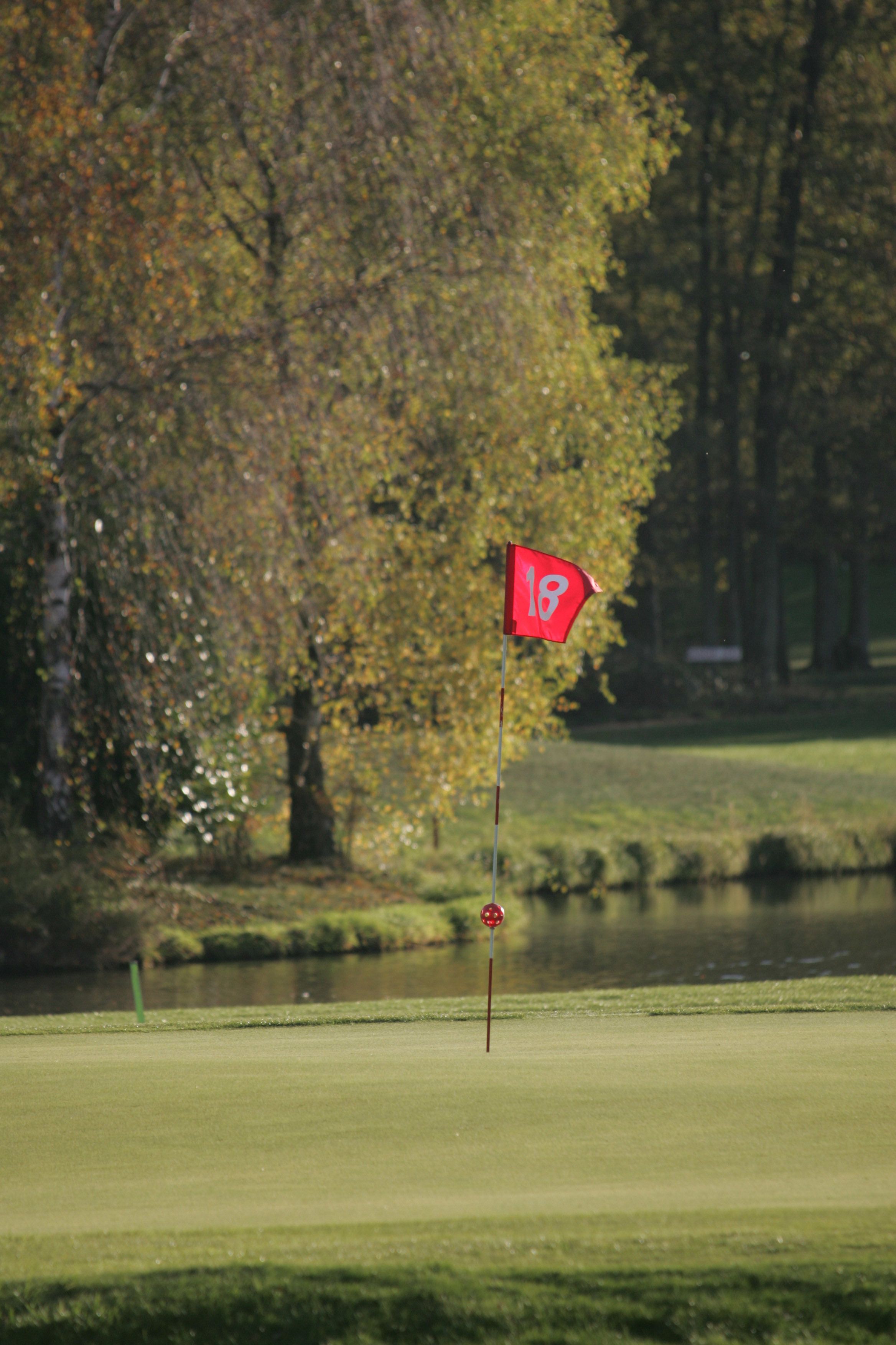A golf course with a red flag marking the 18th hole.