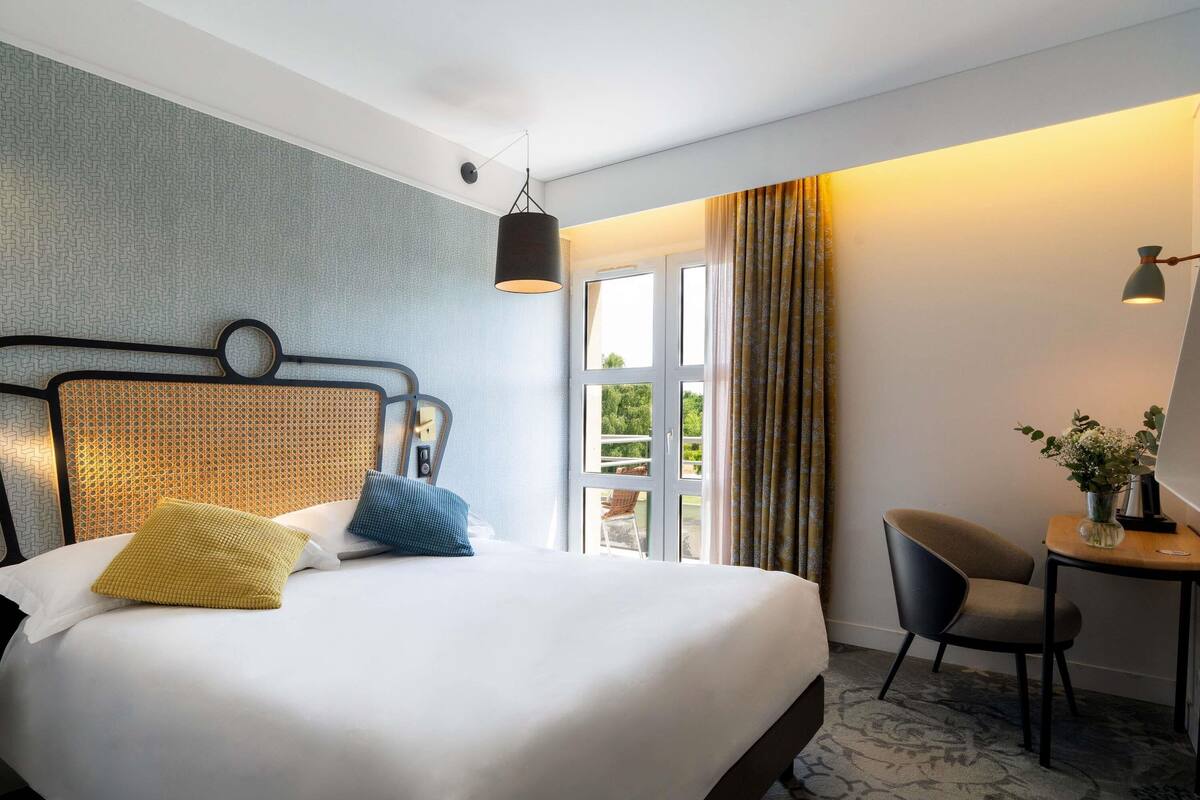Quarto de hotel com uma cama, uma mesa e uma cadeira.