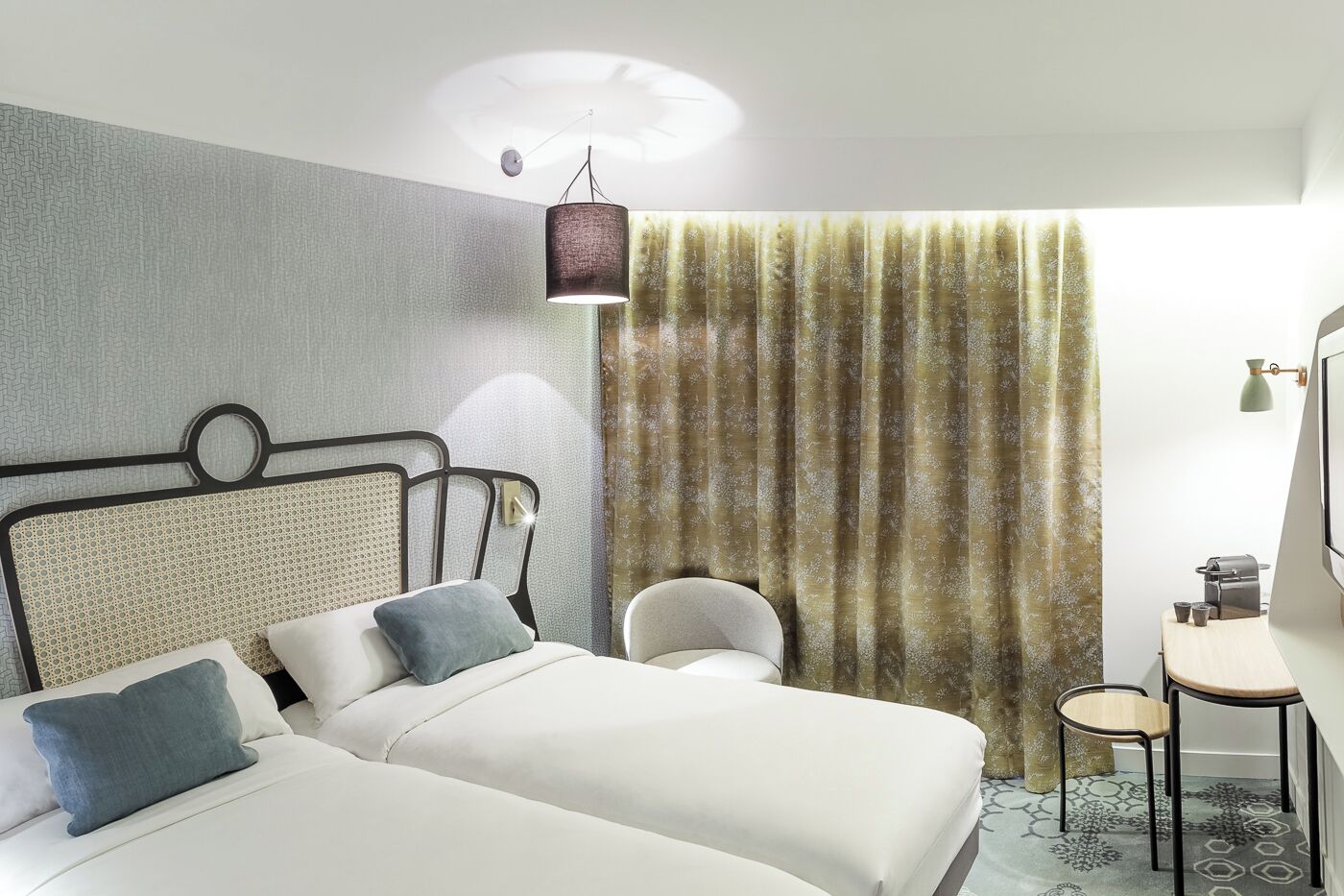 A hotel room with a bed, a chair, a desk, and a curtain.