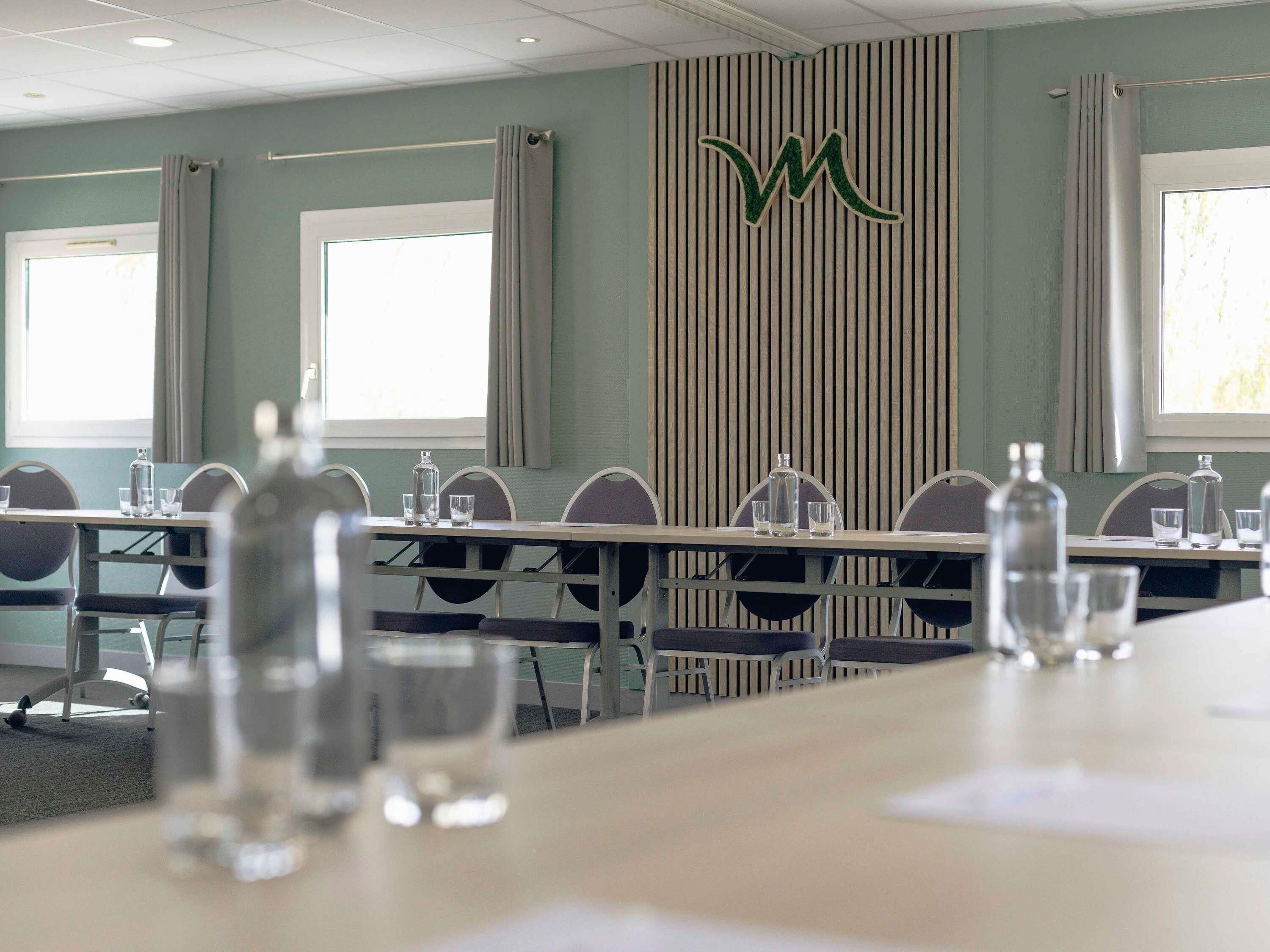 Una sala de conferencias con mesas, sillas y botellas de agua.
