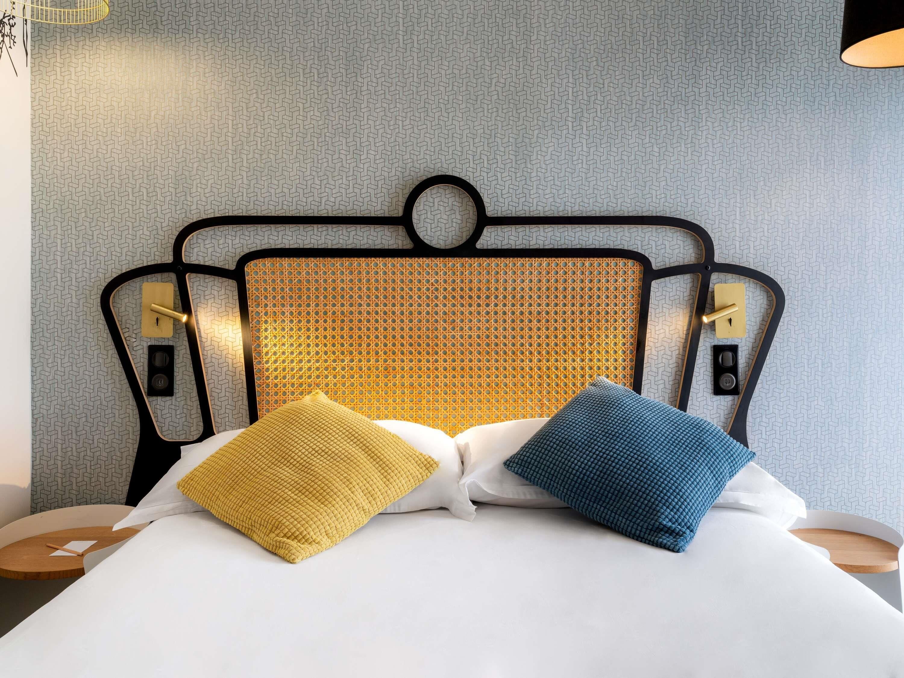 A bed with a headboard, two bedside tables, and a patterned wall.