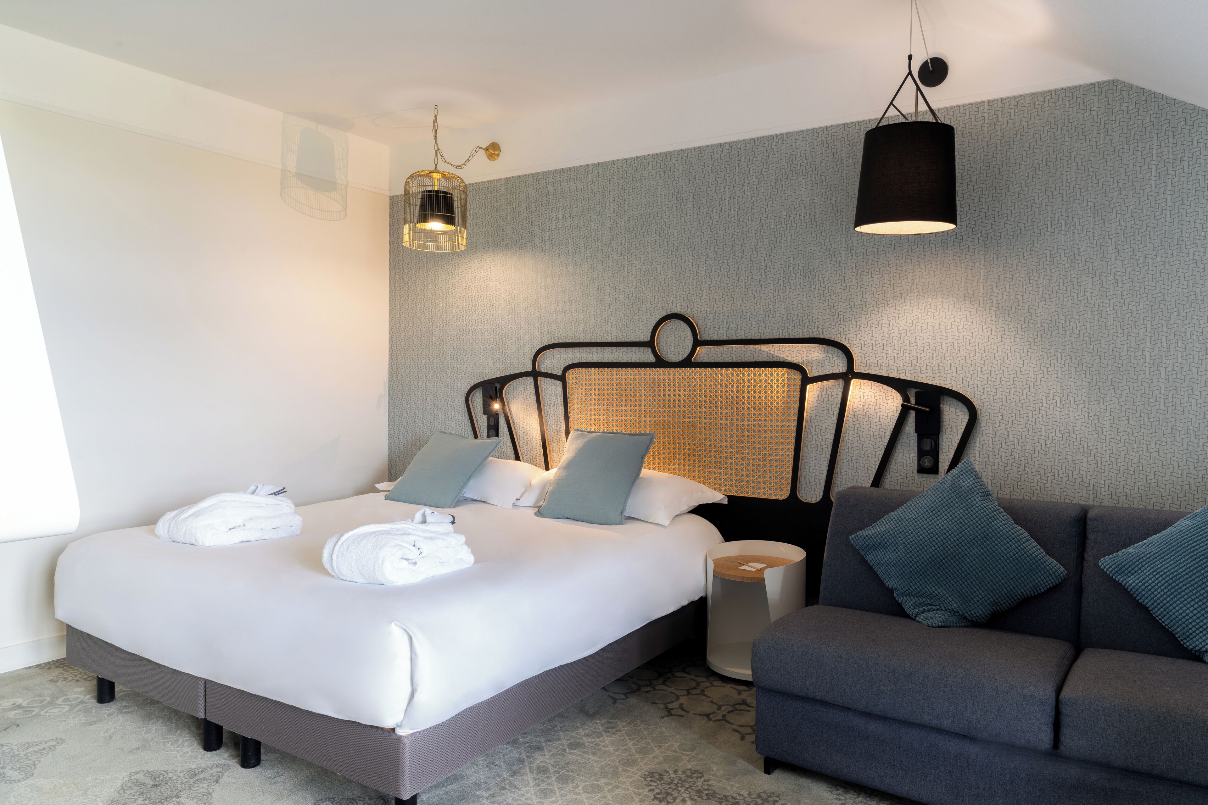 Een moderne hotelkamer met een groot bed, een bank en een bijzettafeltje.