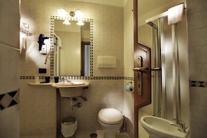 Et badeværelse med håndvask, toilet og bruser.