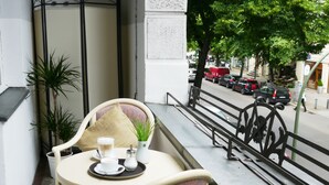 A balcony with a table set for two, a potted plant, and a view of the street with parked cars. - Astrid Hotel am Kurfürstendamm (Berlin)
