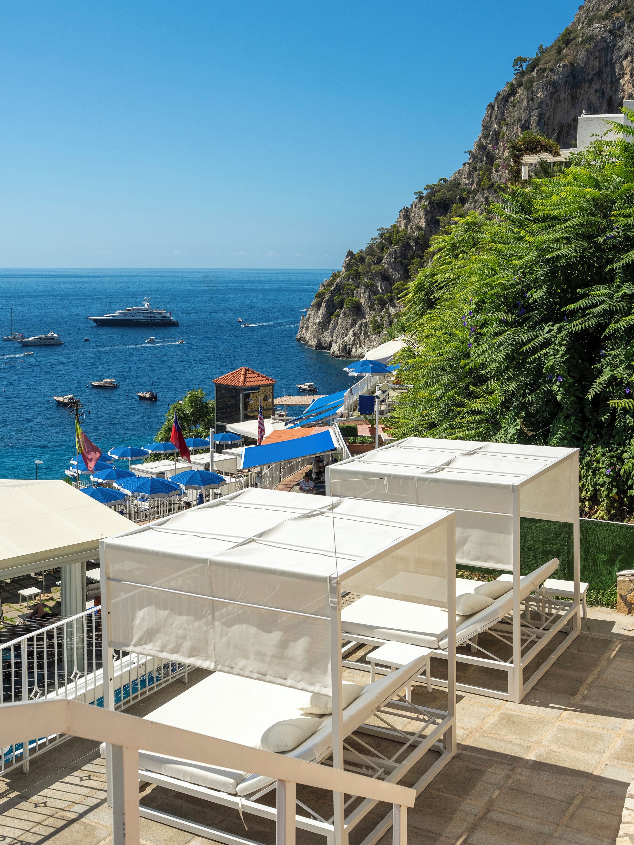 A coastal hotel with outdoor seating and a view of the sea.