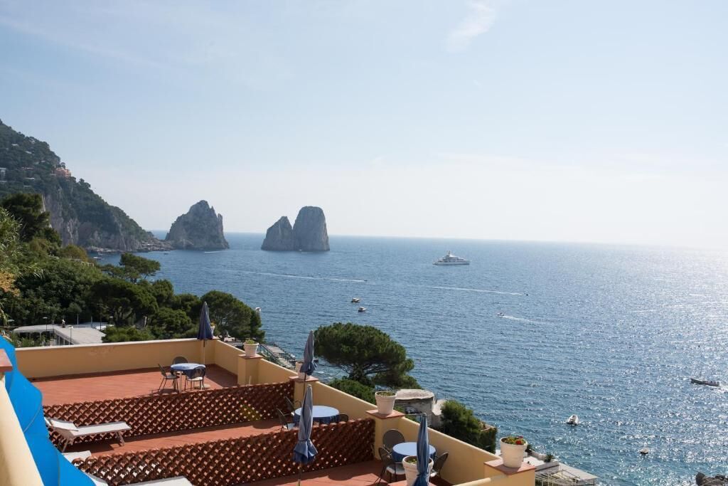 A terrace with outdoor seating overlooking a coastal view, including rocky formations and the sea.