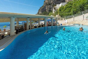 Una piscina al aire libre, sombrillas, sillones reclinables de piscina