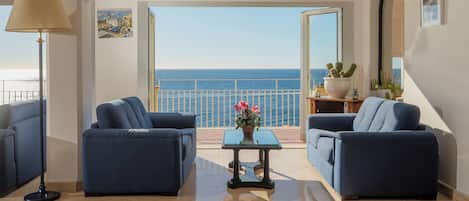 A modern living room with two sofas, a coffee table, and a view of the sea.