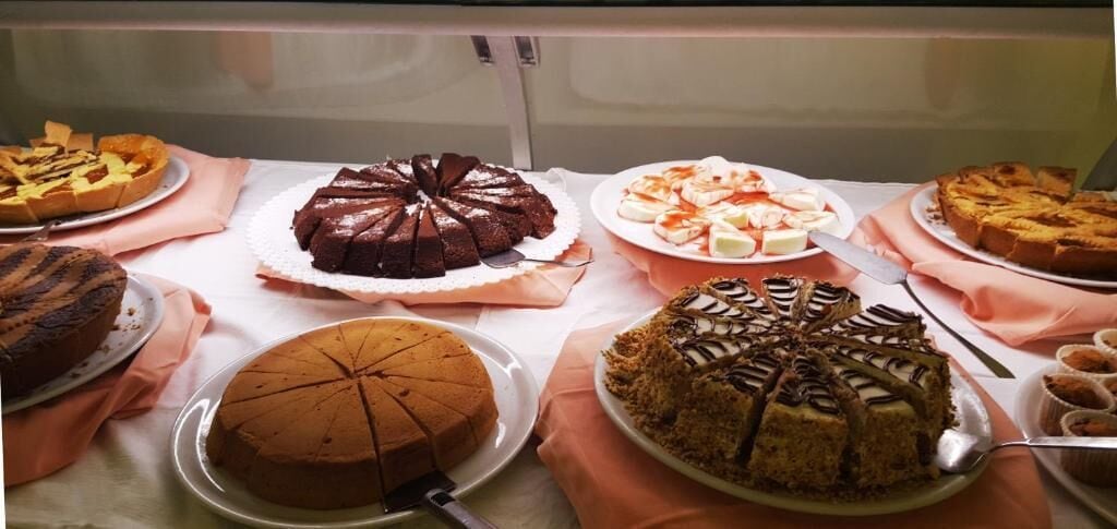 A display of various cakes on a table with a white tablecloth.