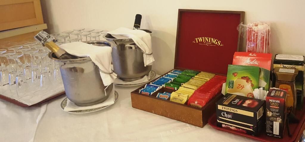 Una mesa con una botella de vino, copas, una olla, una caja de té Twinings y una caja de té Chai.