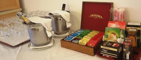 Una mesa con una botella de vino, copas, una olla, una caja de té Twinings y una caja de té Chai.