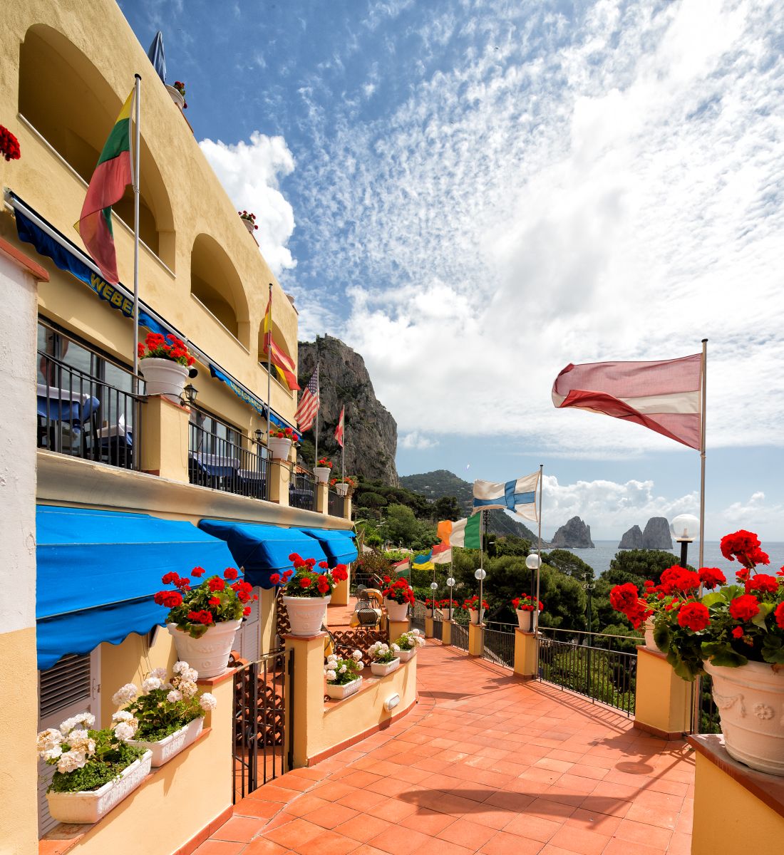 Un balcon agrémenté de pots de fleurs, de drapeaux et offrant une vue sur la mer.