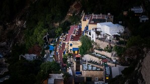 An aerial view of Hotel Weber with a pool, multiple floors, and a stone wall. - Hotel Weber Ambassador (Capri)