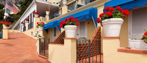 Um hotel com caminhos de telha de barro, varandas adornadas com flores vermelhas e bandeiras.