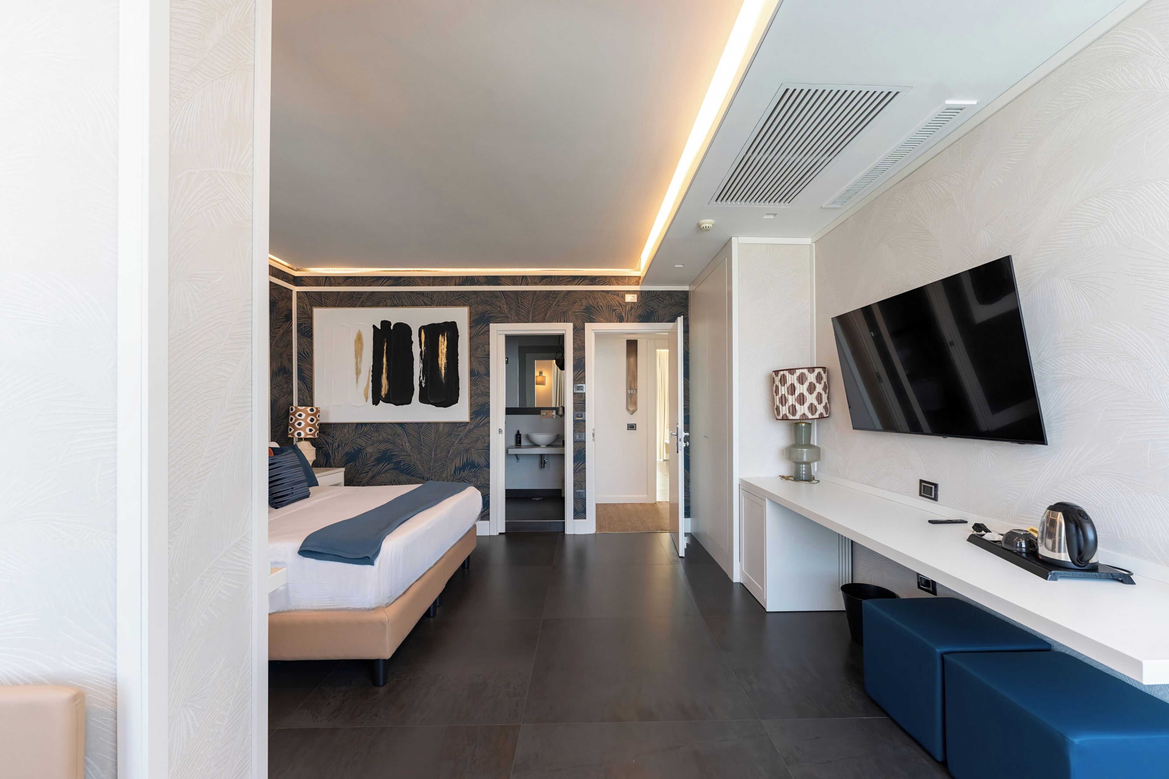 Ein modernes Hotelzimmer mit Bett, Fernseher, Schreibtisch und Bad.