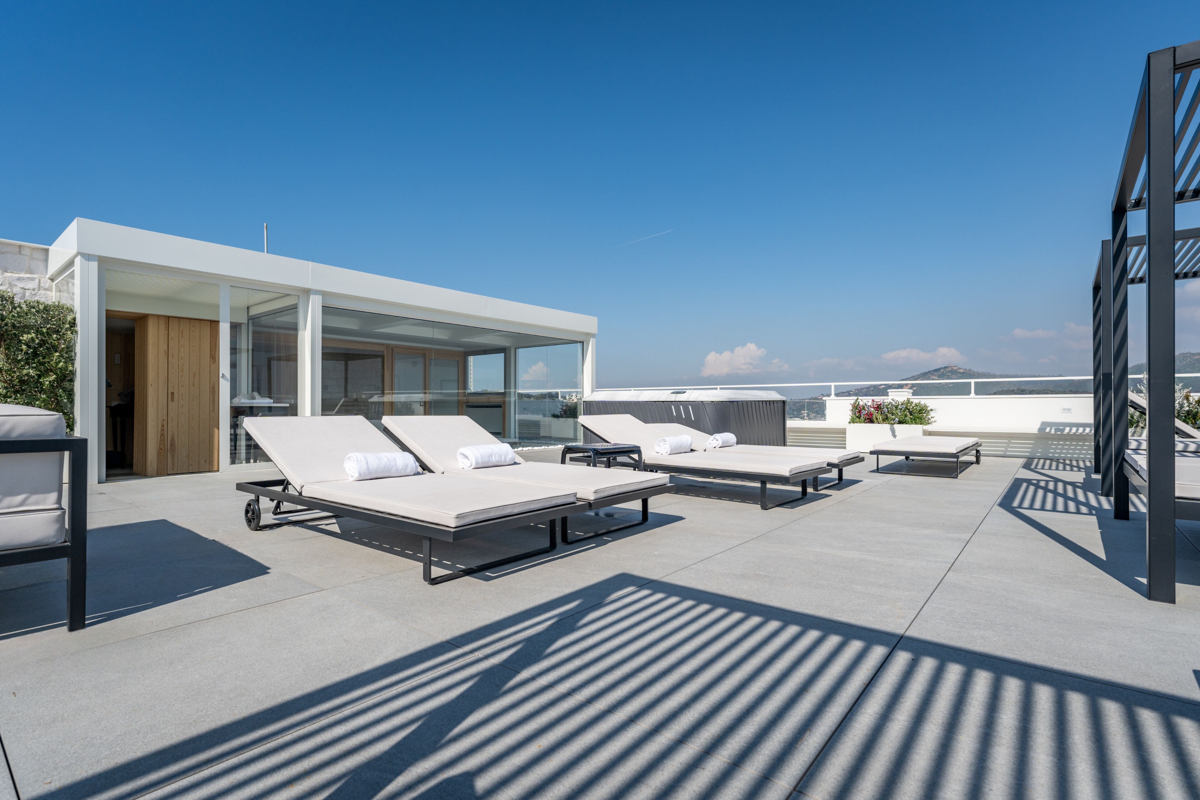 Eine Dachterrasse mit Liegestühlen und einem gläsernen Gebäude.