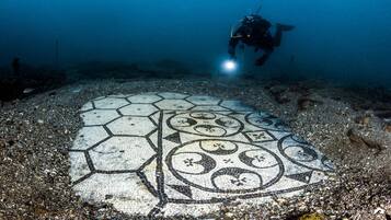 Un plongeur explore une mosaïque immergée au fond de l’océan.