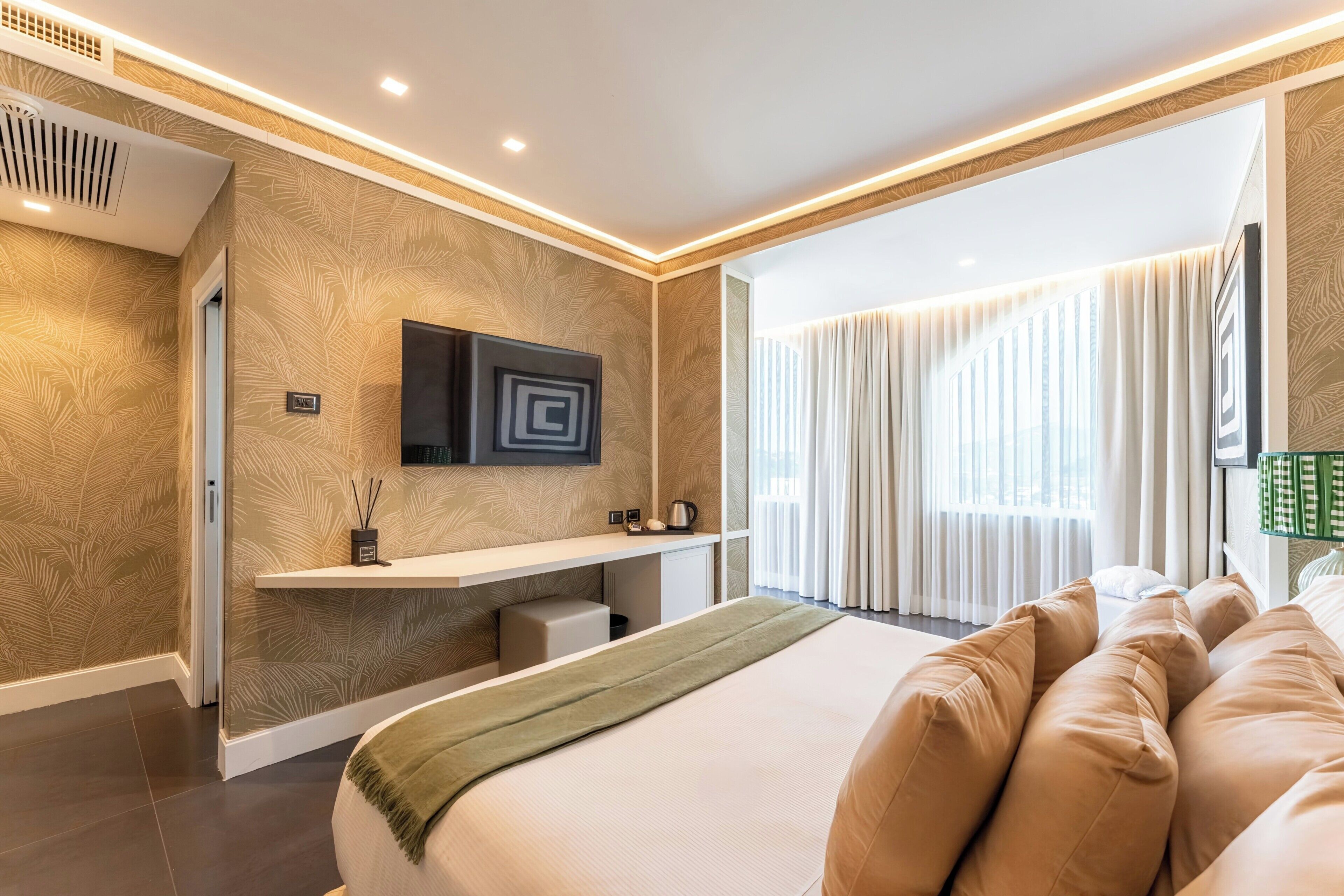 A modern bedroom with a large bed, a flat-screen TV, a bedside table, and a window with curtains.