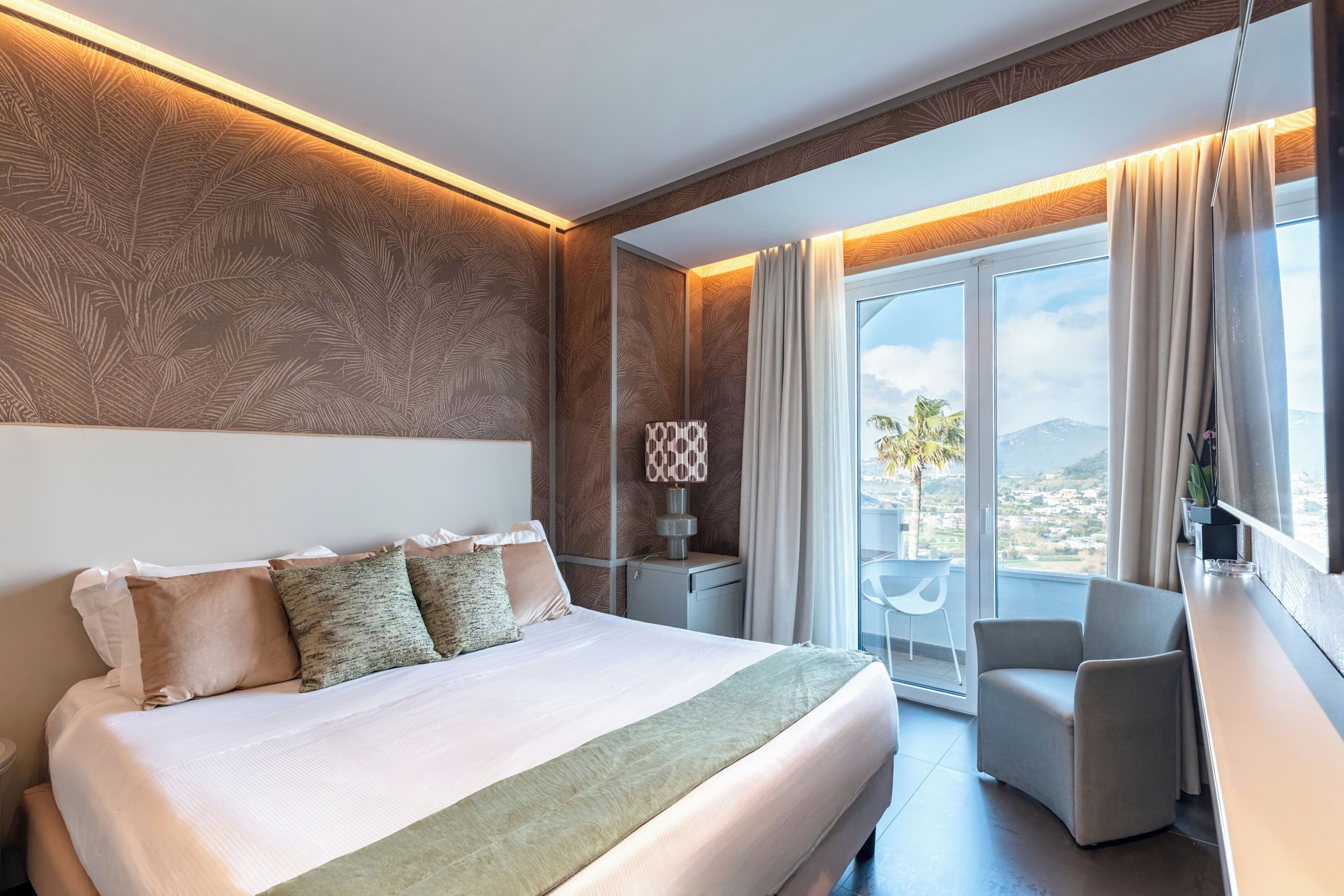 Una habitación de hotel moderna con una cama grande, un escritorio, una silla y un balcón con vistas.