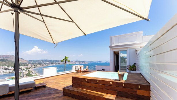 A rooftop terrace with a pool, wooden deck, outdoor seating, and a view of the sea and city. - Hotel Il Gabbiano (Bacoli)