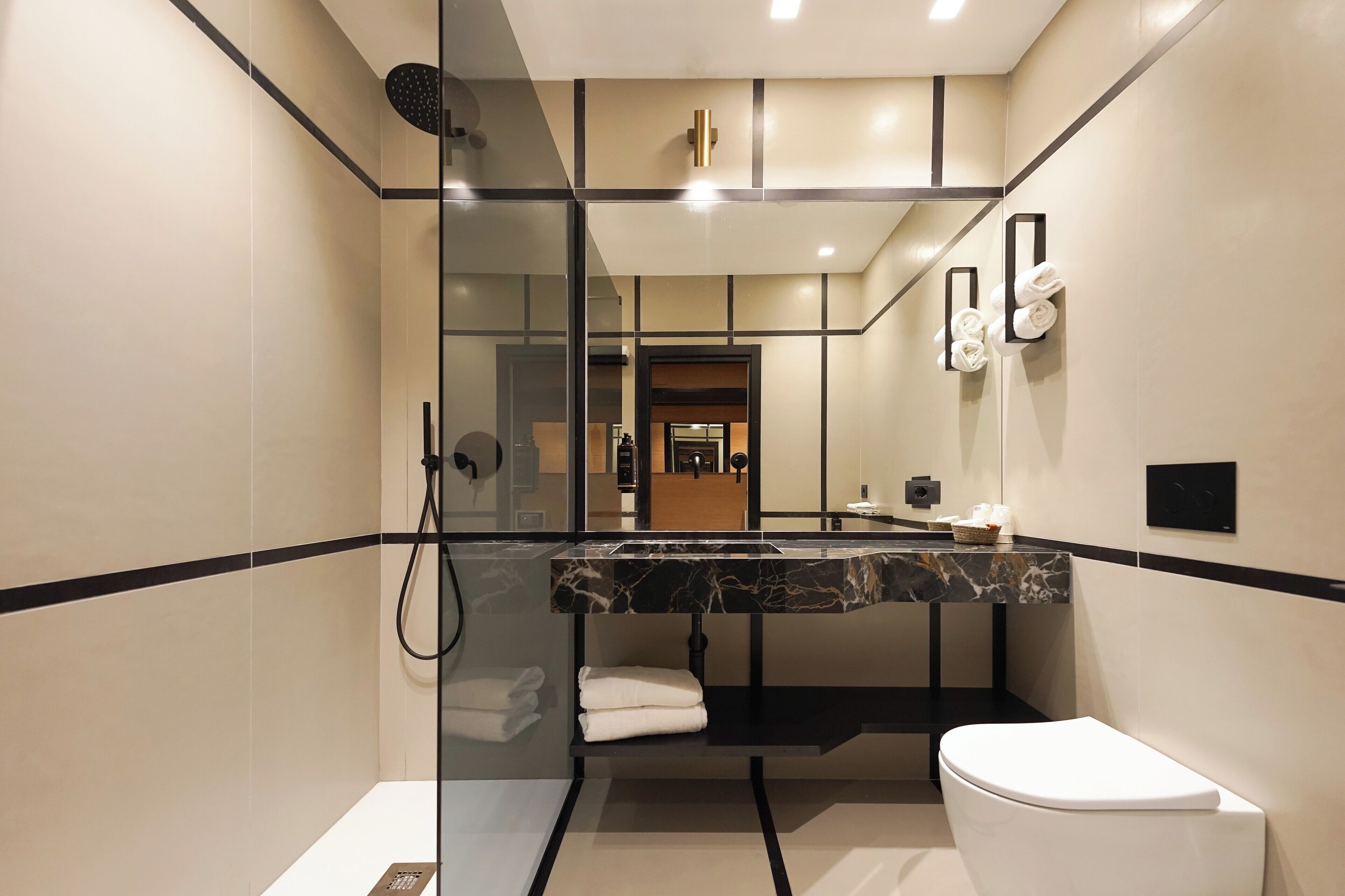 A modern bathroom with a glass-enclosed shower, a marble countertop, and a white toilet.