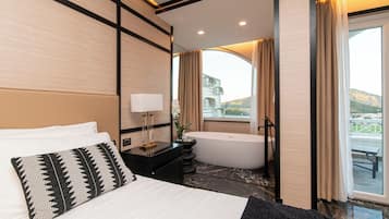 Habitación de hotel moderna con una cama grande, una bañera y vistas al exterior.