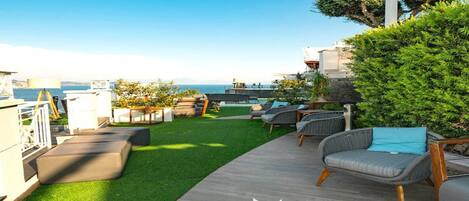 Un espacio al aire libre con vistas al mar, amueblado con sillas de mimbre y una terraza de madera.