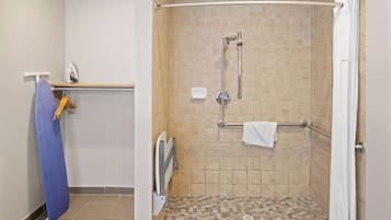 A shower area with a tiled floor, a handrail, and a towel rack.