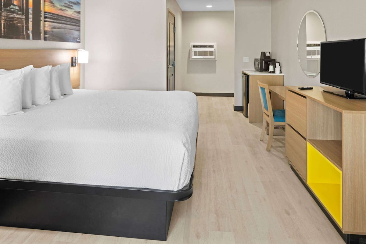 Ein Hotelzimmer mit Bett, Schreibtisch, Fernseher, Spiegel und Klimaanlage.