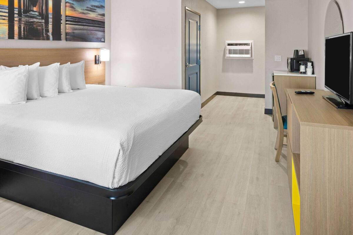 Ein Hotelzimmer mit einem großen Bett, einem Schreibtisch mit Fernseher und einer Kaffeemaschine.
