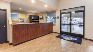 A reception area with a wooden counter, framed pictures on the wall, and a view of the parking lot through the glass door. - Days Inn by Wyndham San Diego-East/El Cajon (El Cajon)