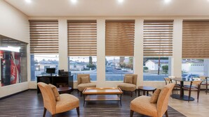 A spacious lobby with a modern design, featuring a seating area with sofas and a coffee table, large windows with blinds, and a visible Coca-Cola advertisement. - Days Inn by Wyndham San Diego-East/El Cajon (El Cajon)