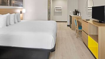 A hotel room with a bed, a desk, a chair, a television, and a mirror.